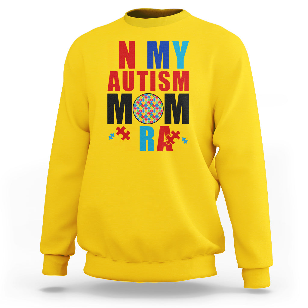 Yellow sweatshirt with colorful Autism Mom puzzle-piece graphic, crewneck long sleeves.
