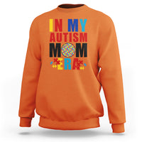 Orange sweatshirt with colorful Autism Mom puzzle-piece graphic, crewneck long sleeves.