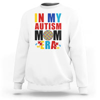 White sweatshirt with colorful Autism Mom puzzle-piece graphic, crewneck long sleeves.