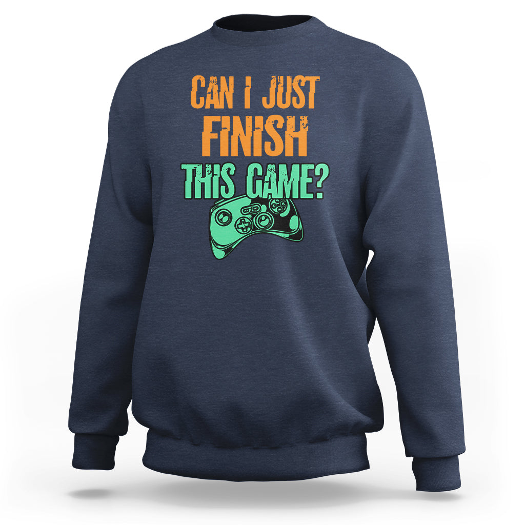 Navy crewneck sweatshirt with colorful “Can I just finish this game?” gamepad graphic.