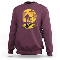 Maroon sweatshirt with yellow moon Bigfoot alien UFO silhouette graphic