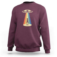 Maroon crewneck sweatshirt with alien abduction graphic and UFO beam print.