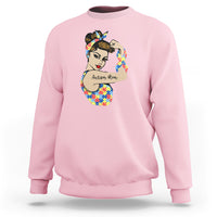 Pink crewneck sweatshirt with autism-themed face graphic on chest.