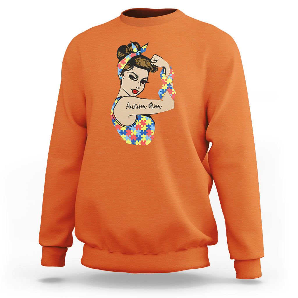 Orange crewneck sweatshirt with autism-themed face graphic on chest.