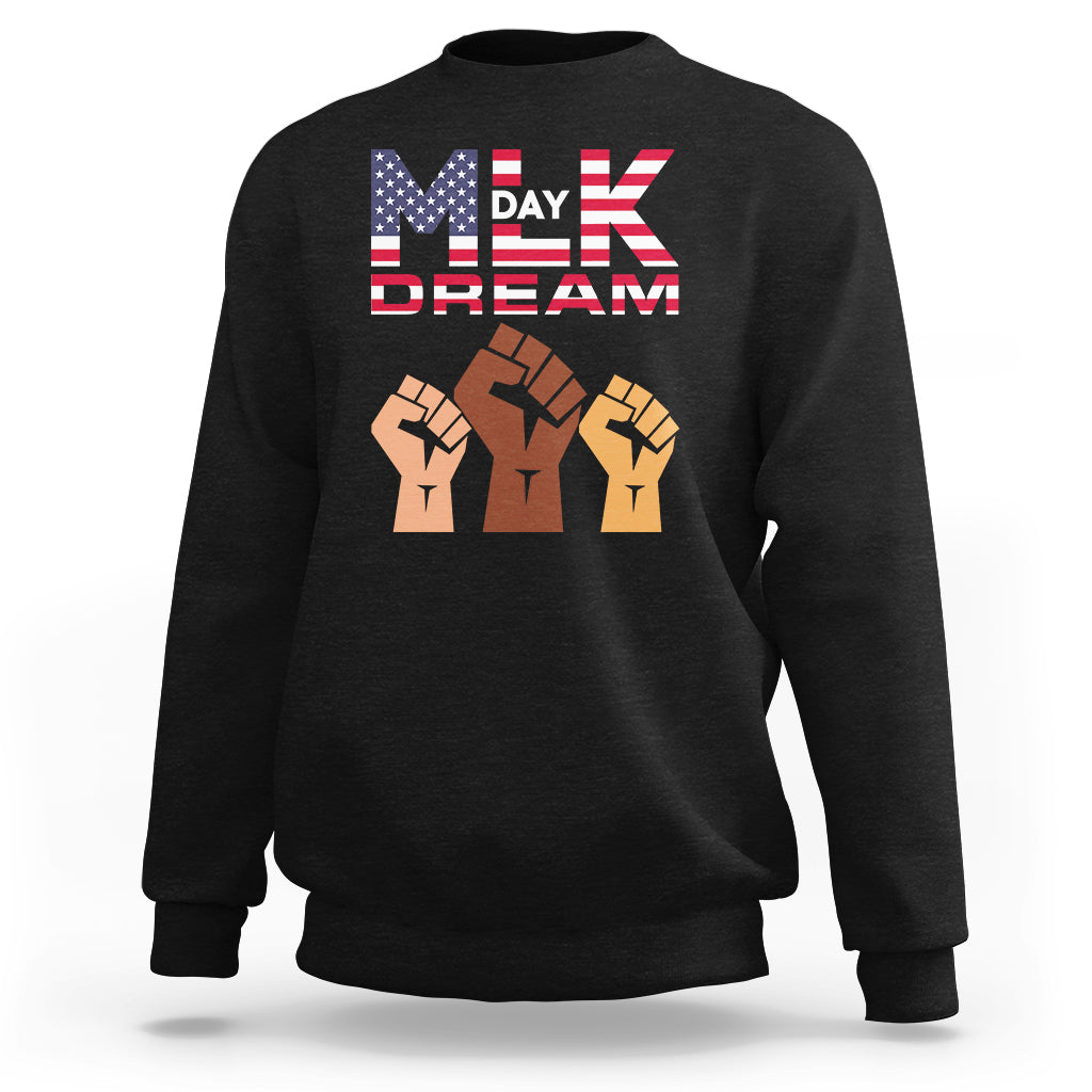 Black crewneck sweatshirt with “MLK Day Dream” graphic and raised-fist design on chest