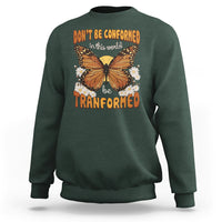 Dark green crewneck sweatshirt with front butterfly graphic and “be transformed” inspirational text
