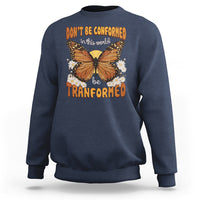 Navy crewneck sweatshirt with front butterfly graphic and “be transformed” inspirational text