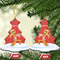 Red bell-shaped ceramic ornament held in hands, with gingerbread runner and gold loop.
