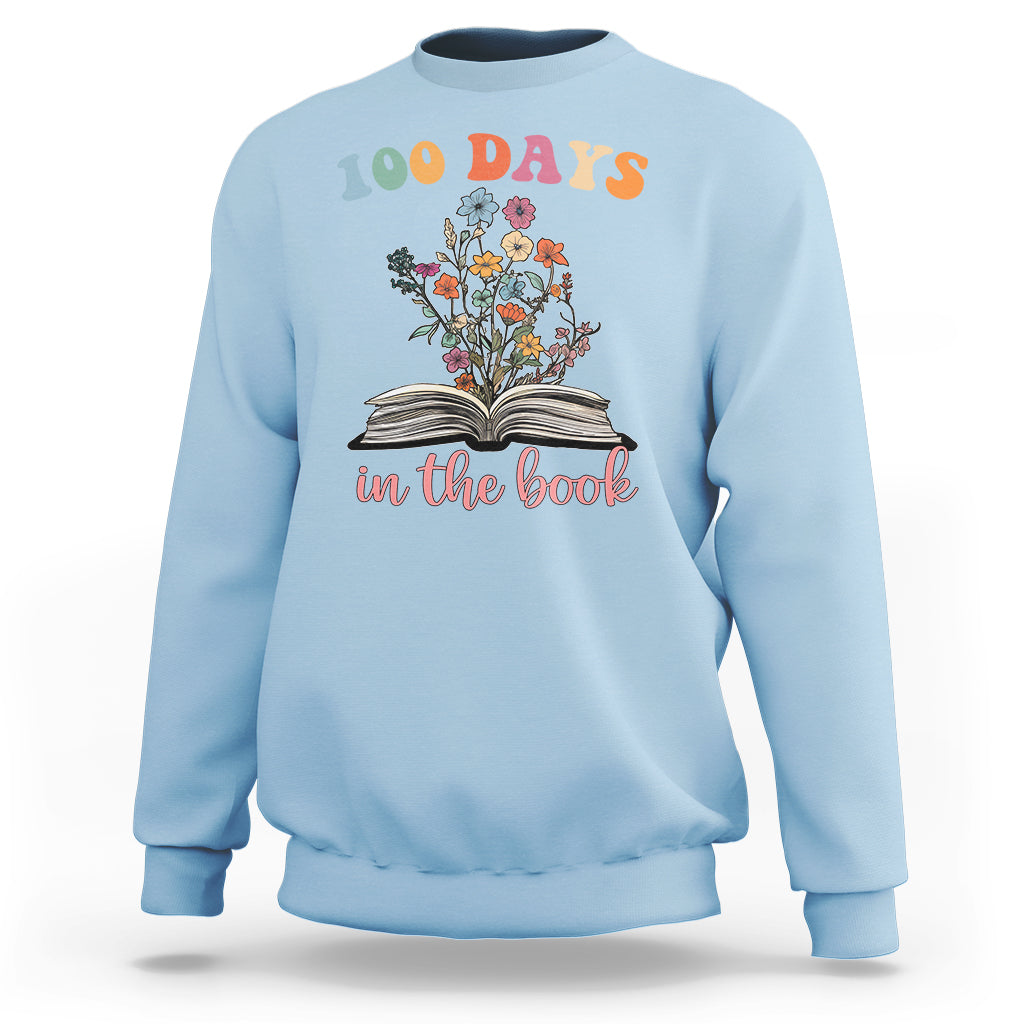 Light blue crewneck sweatshirt with “100 Days” floral open-book “in the book” graphic
