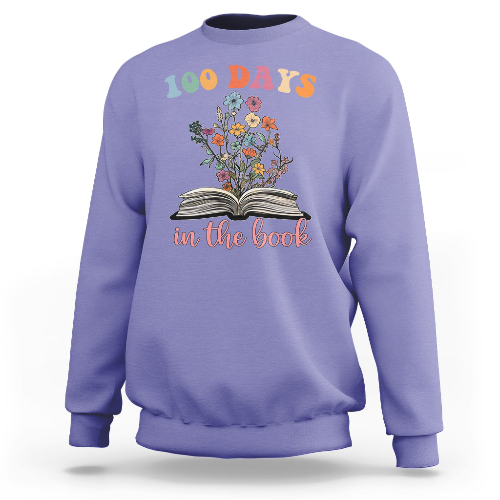 Violet crewneck sweatshirt with “100 Days” floral open-book “in the book” graphic
