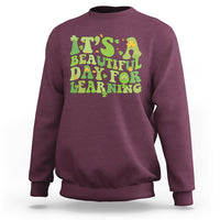 Maroon students sweatshirt with green and yellow text graphic: "It's Beautiful Day for Learning".