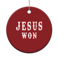 Red round Christmas ornament with 'JESUS WON' lettering, hanging with gold string.