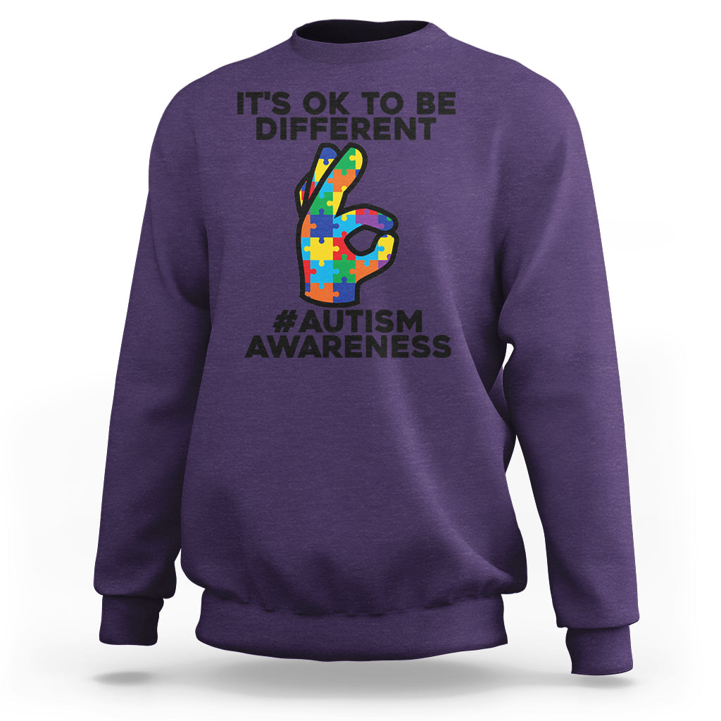 Purple crewneck sweatshirt with “It’s OK to be different” and puzzle-style 3 graphic