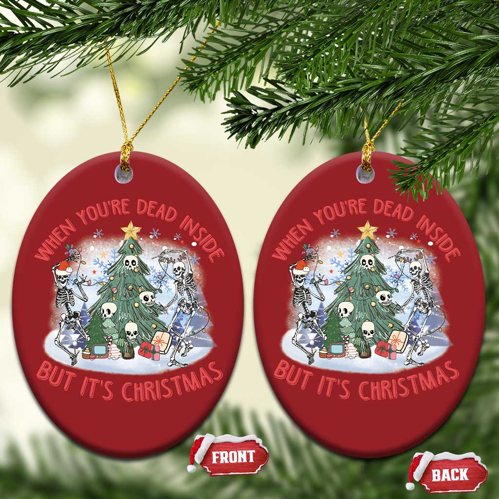Two red oval Christmas ornaments with skeleton scene, hanging on tree branches