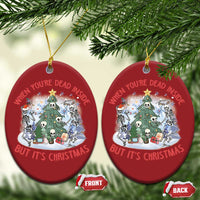 Two red oval Christmas ornaments with skeleton scene, hanging on tree branches