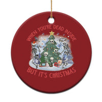 Red round Christmas ornament with cartoon skeletons around a decorated tree