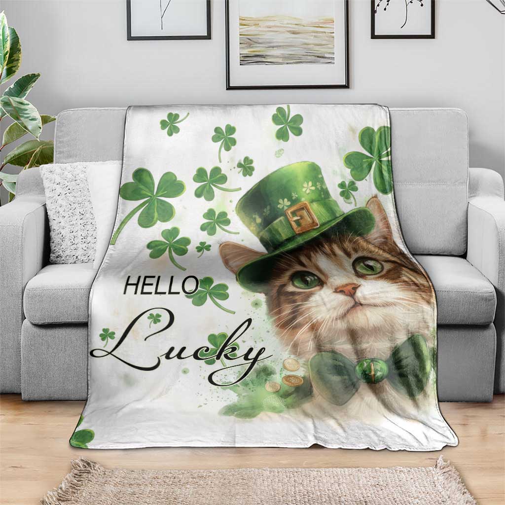Cat print throw blanket on a couch: white base, green clovers, leprechaun hat, “Hello Lucky”