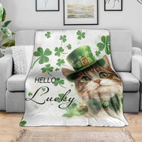 Cat print throw blanket on a couch: white base, green clovers, leprechaun hat, “Hello Lucky”