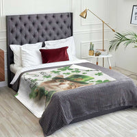 Cat-themed throw blanket on a bed: white fabric with green clovers, leprechaun hat, “Hello Lucky”