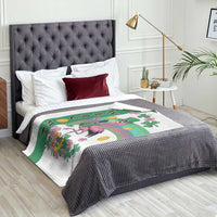Flamingo welcome throw blanket on bed, white base with green shamrock stripe and WELCOME