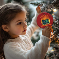 Child holding a red round Christmas ornament with burning dumpster graphic and slogan.