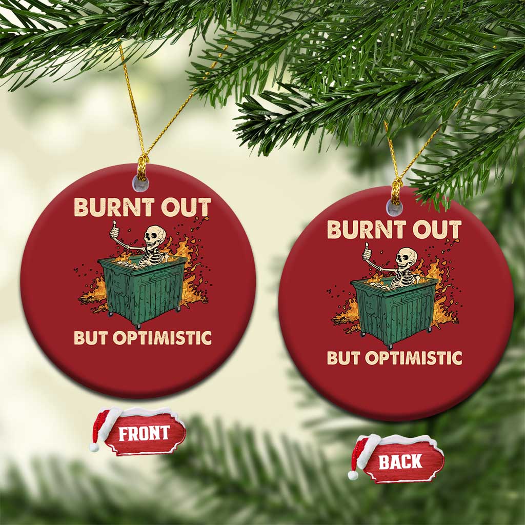Two red round Christmas ornaments showing skeleton dumpster graphic and “Burnt out, but optimistic”.