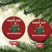 Two red round Christmas ornaments showing skeleton dumpster graphic and “Burnt out, but optimistic”.
