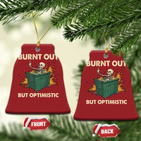 Two red bell-shaped Christmas ornaments with skeleton dumpster art and “Burnt out, but optimistic”.