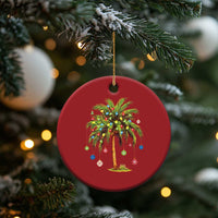 Red round palm tree Christmas ornament with multicolor lights hanging from a tree branch.
