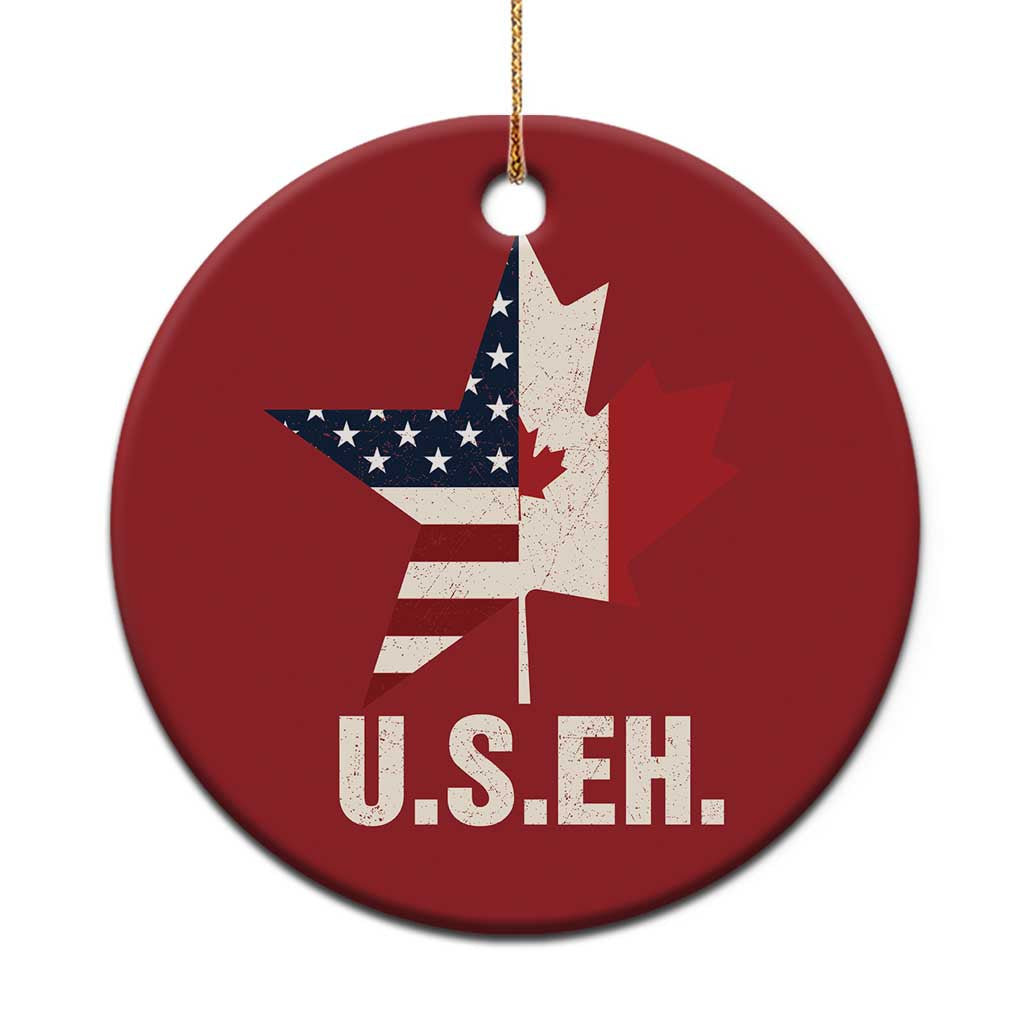 Red round holiday ornament with Canada maple leaf and U.S.EH text, gold hanging loop