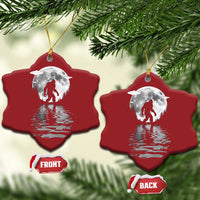 Two red bell-shaped Bigfoot Christmas ornaments with silver moon and reflection