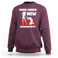 Maroon crewneck sweatshirt with “Soon Under New Management” graphic
