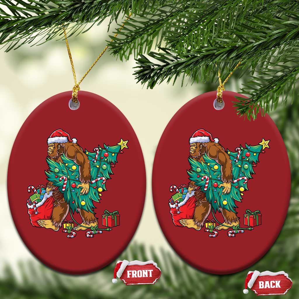 Two red oval Bigfoot Christmas ornaments with Santa hat, decorated tree and gift boxes