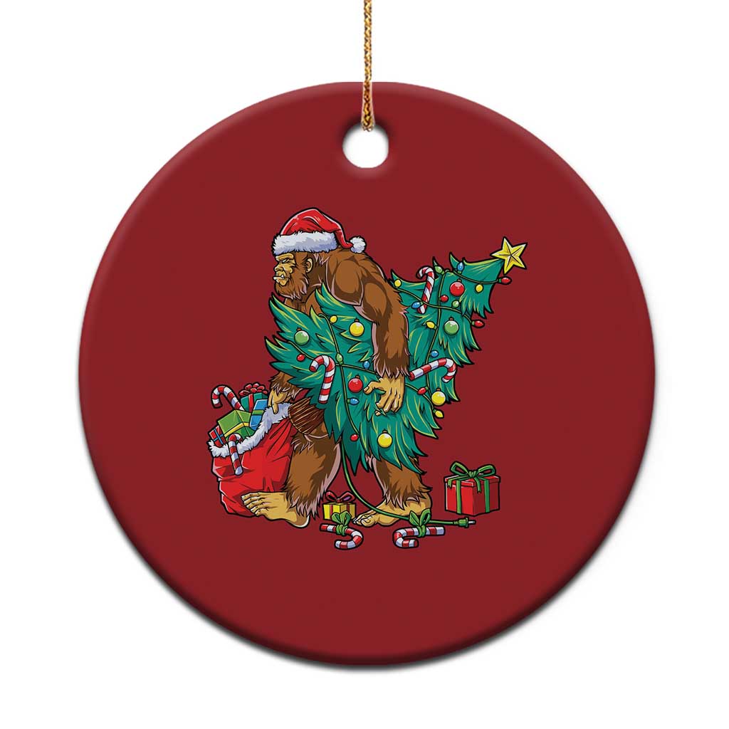 Red round Bigfoot Christmas ornament with Santa hat, decorated tree and gift boxes