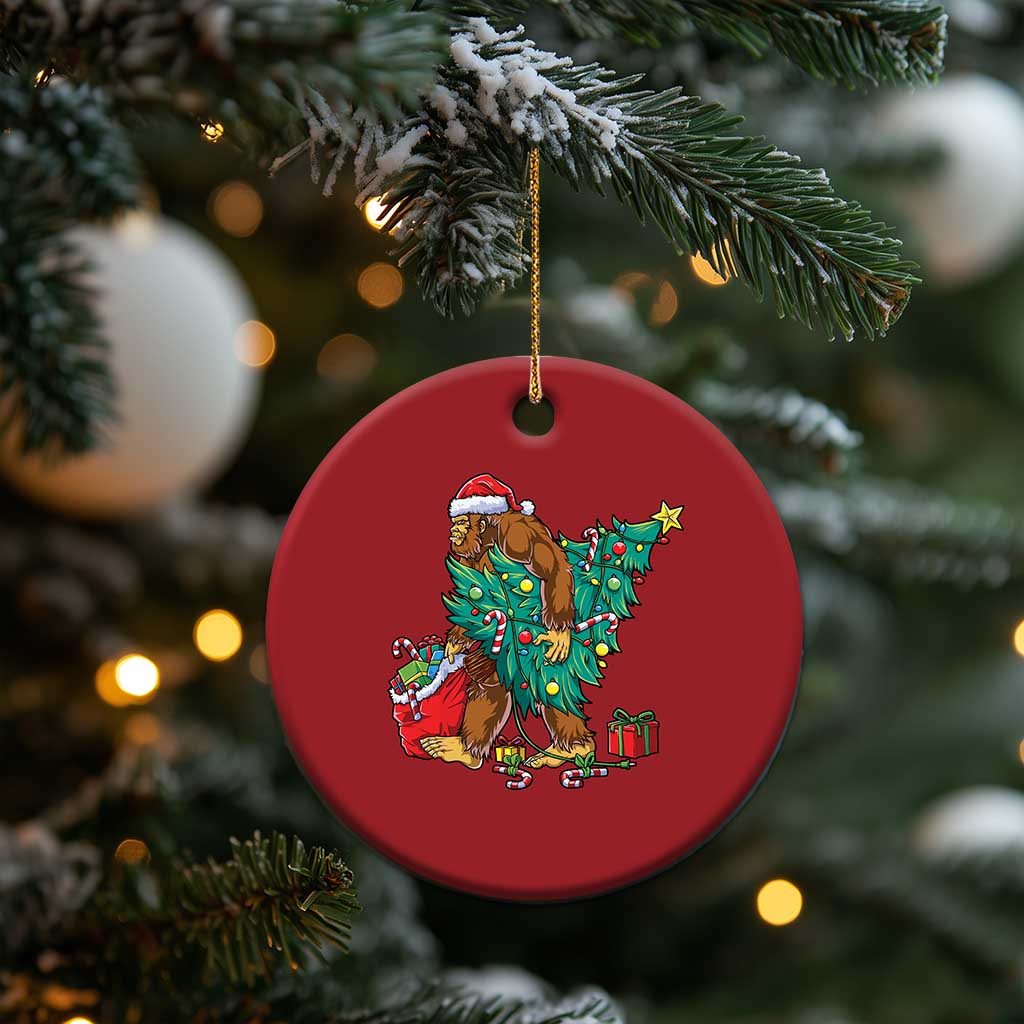 Red round Bigfoot Christmas ornament featuring Santa hat, decorated tree and gift boxes
