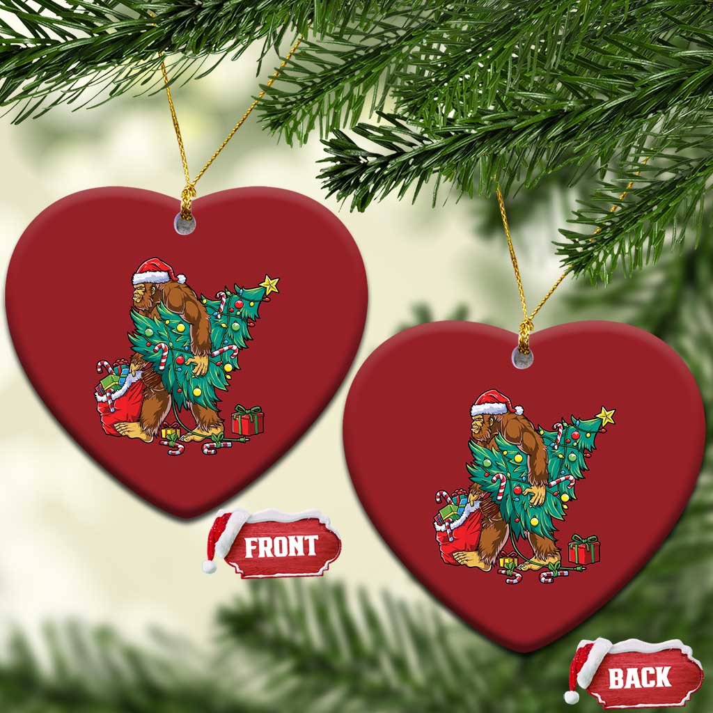 Two red heart-shaped Bigfoot Christmas ornaments with Santa hat, decorated tree and gifts