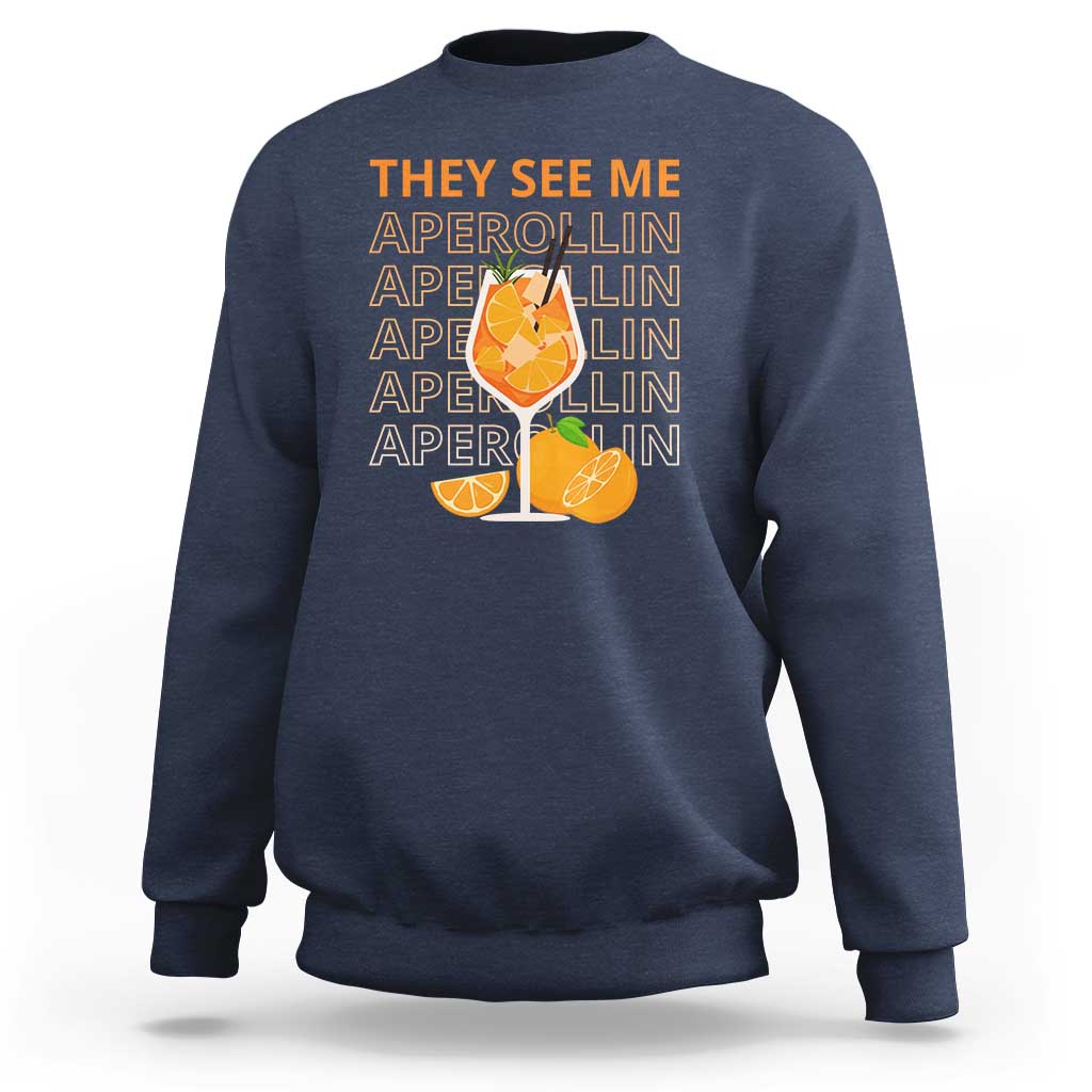 Navy sweatshirt with “THEY SEE ME” Aperol-lin text and citrus cocktail graphic on back