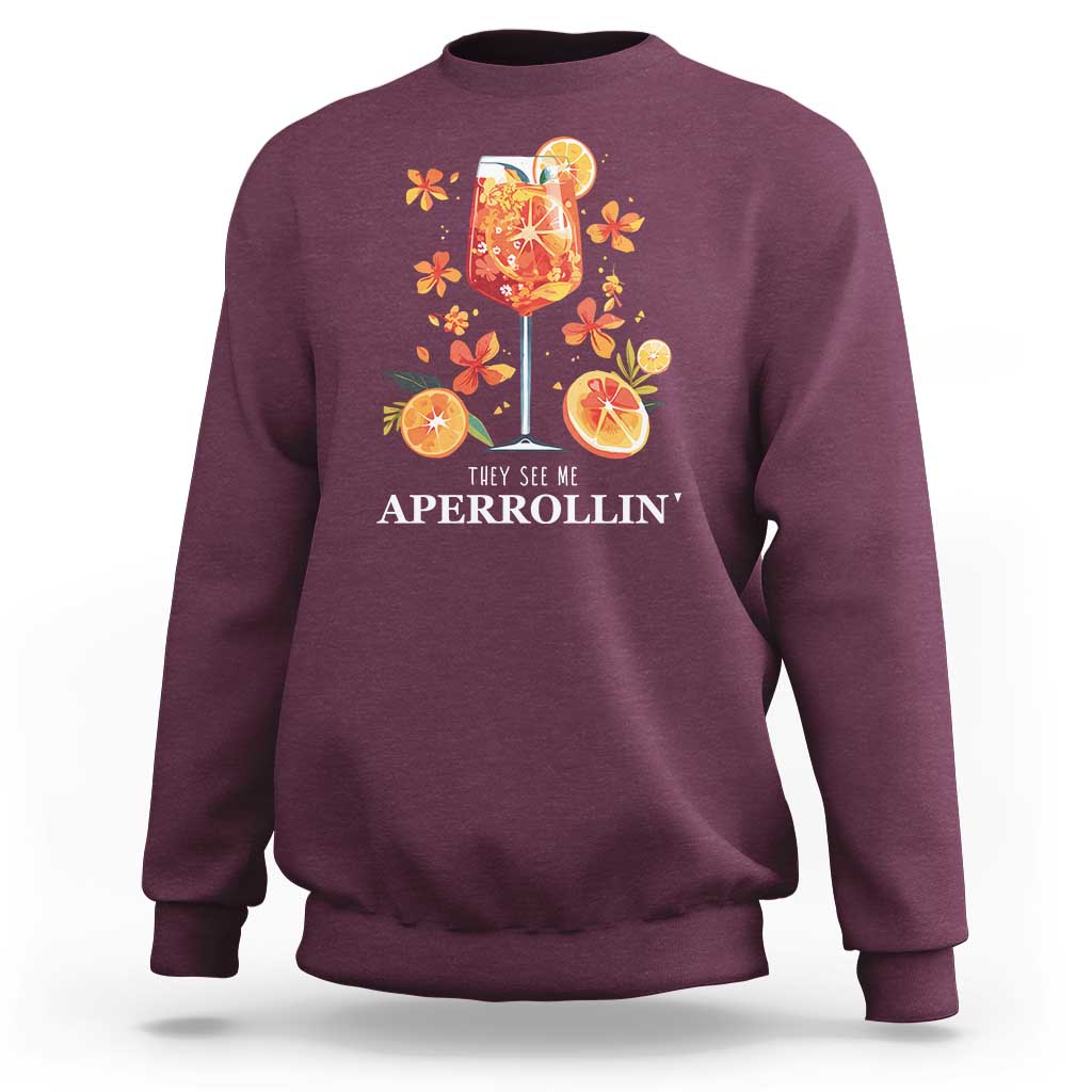 Maroon sweatshirt with front citrus cocktail graphic and “They see me APERROLLIN’” text