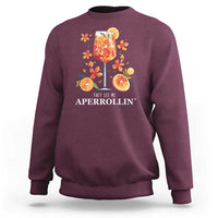 Maroon sweatshirt with front citrus cocktail graphic and “They see me APERROLLIN’” text