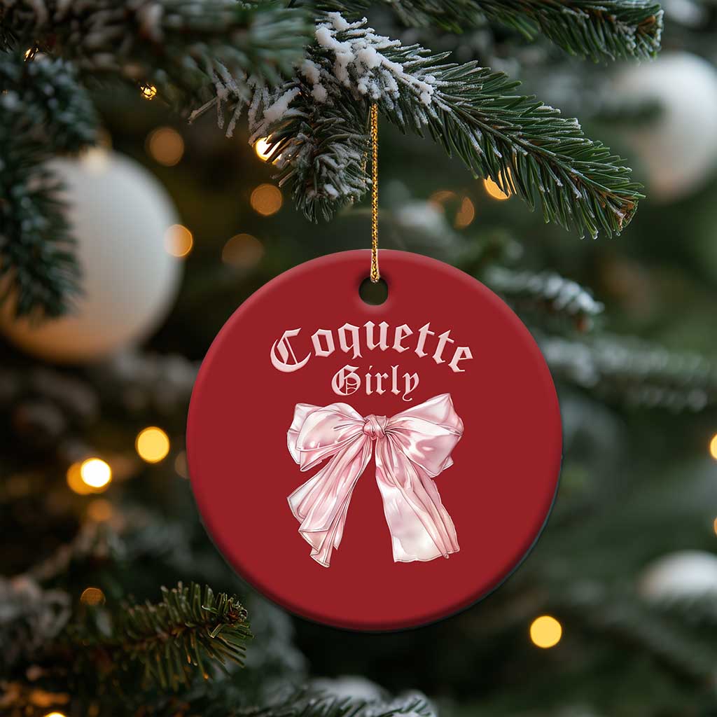 Red round Christmas ornament with pink bow, hanging on a tree with gold string