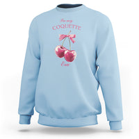 Light blue sweatshirt with bow and cherry graphic, crewneck and long sleeves.