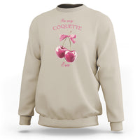 Sand-colored sweatshirt with bow and cherry graphic, crewneck and long sleeves.