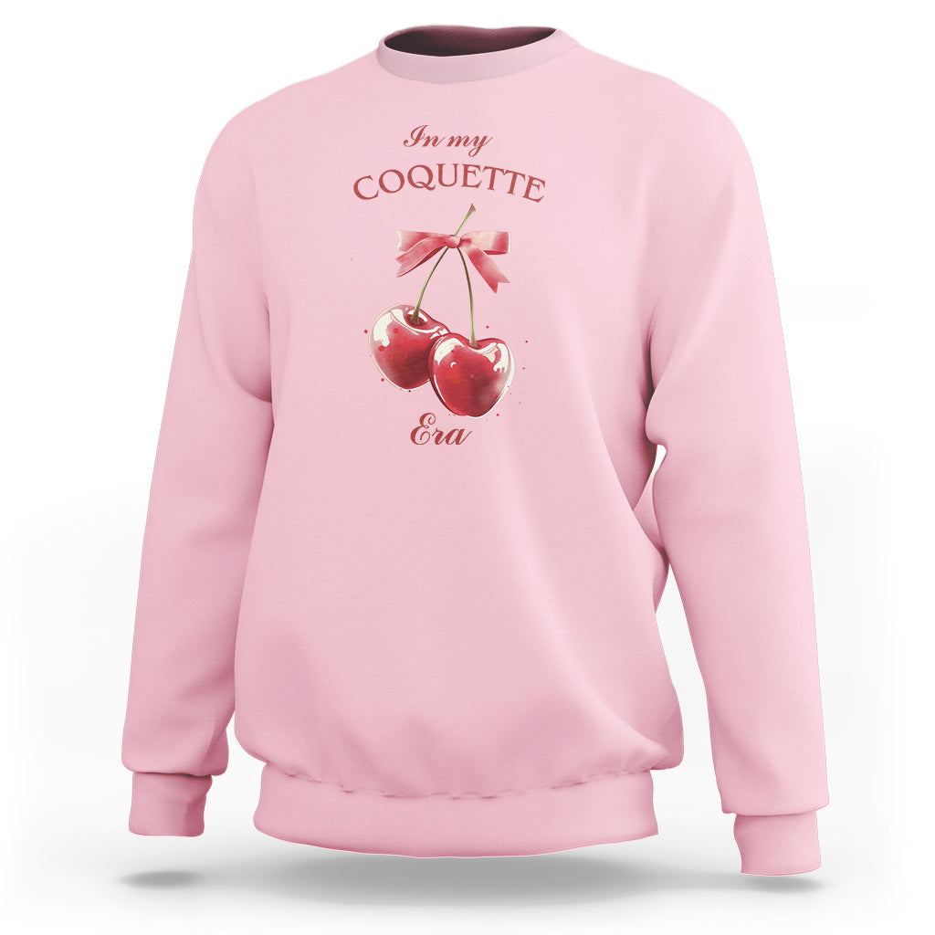 Light pink sweatshirt with cherry and bow graphic at chest, crew neck