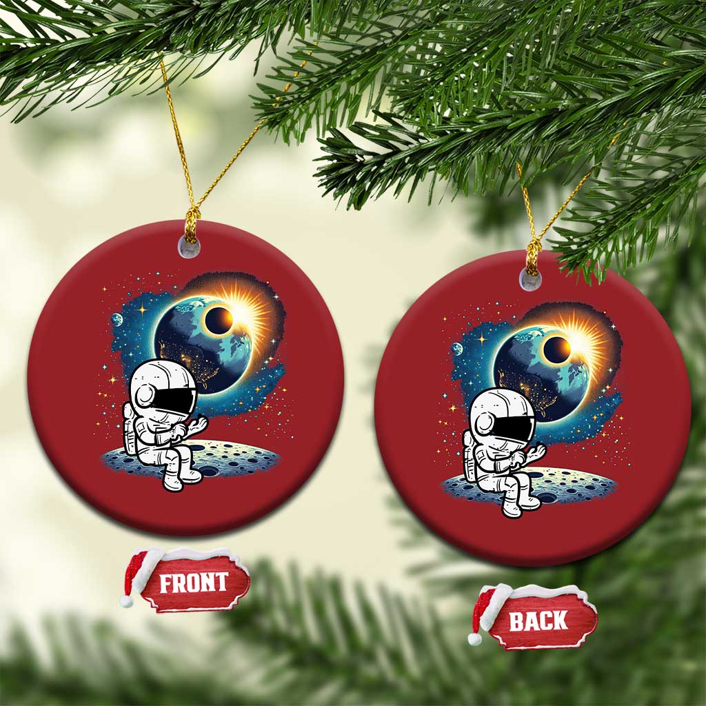 Two red round astronaut space ornaments hanging from green pine branches