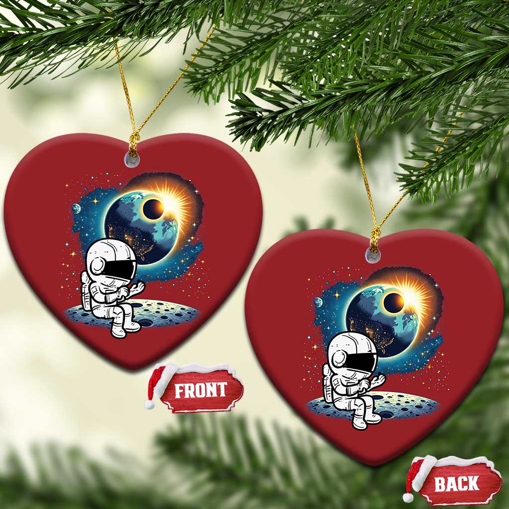 Two red heart-shaped astronaut space ornaments hanging from pine branches
