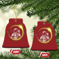 Two red bell-shaped astronaut Christmas ornaments with glowing space scene and gold loops