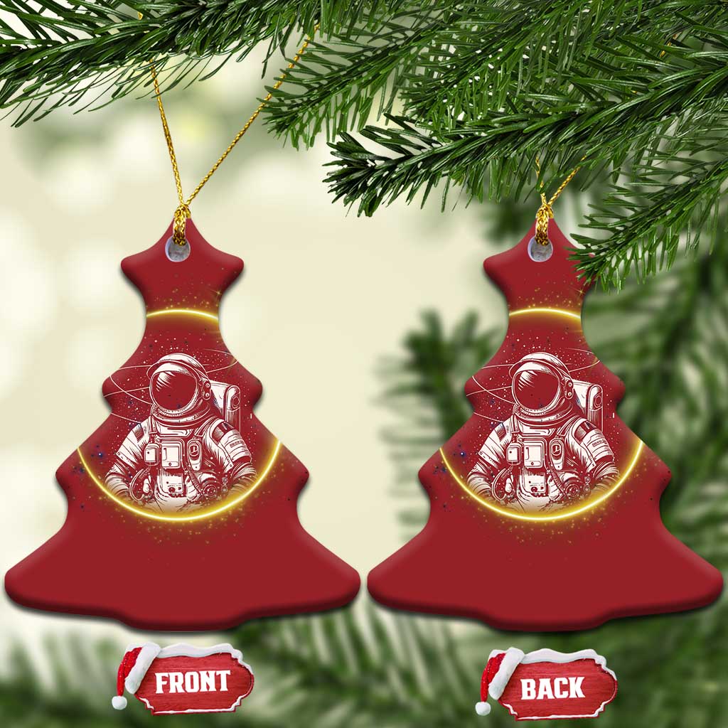 Two red tree-shaped astronaut Christmas ornaments with glowing space art and gold hanging loops