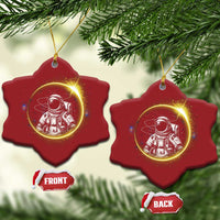 Two red star-shaped astronaut Christmas ornaments with glowing space scene and gold hanging loops