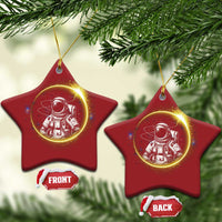 Two red star-shaped astronaut Christmas ornaments with glowing space art and gold hanging loops