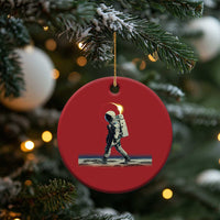 Red round astronaut walking ornament hanging from a Christmas tree with gold cord